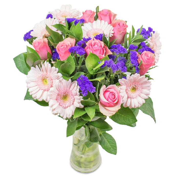 A striking, lovingly arranged bouquet rests in a clear glass vase against a soft background, reflecting the timeless elegance of Finchley Flowers. At its heart are approximately 7 to 9 pink roses-some with petals tightly coiled, others just beginning to open, showcasing spirals that suggest promise and romance. Interspersed with 5 to 7 pale pink Gerbera daisies, whose round, sunlit faces and lighter, almost white centres add vibrance reminiscent of spring strolls through Victoria Park. Bright purple statice clusters offer striking contrast and a gentle wildness, much like the spontaneous beauty in Finchley's quieter hedgerows. Abundant green foliage wraps beneath, lending freshness and a fullness evocative of ancient woodland along the Dollis Valley Greenwalk. The transparent vase displays the stems and fresh-clean water, suggesting a freshly made arrangement ready for swift, same-day delivery across North Finchley or to nearby Muswell Hill. This bouquet, brimming with local character and care, is ideal for celebrating birthdays, anniversaries, or sending heartfelt wishes, embodying both joy and refined affection with a distinctly Finchley touch.